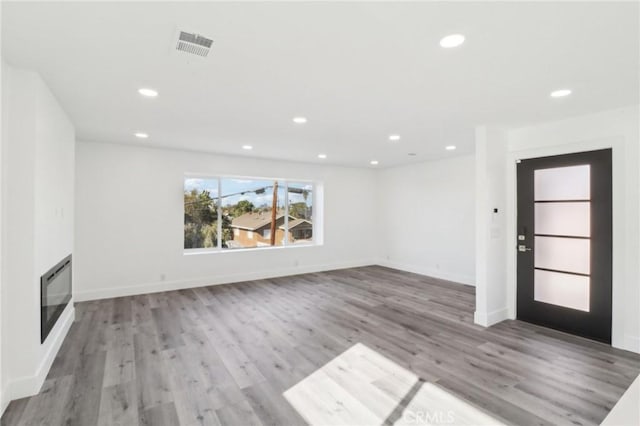 unfurnished living room featuring heating unit and hardwood / wood-style floors