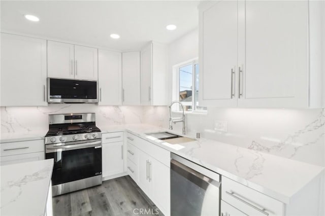 kitchen featuring light stone countertops, stainless steel appliances, white cabinets, and sink