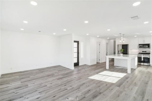 kitchen with decorative light fixtures, a kitchen island, light hardwood / wood-style flooring, appliances with stainless steel finishes, and white cabinets