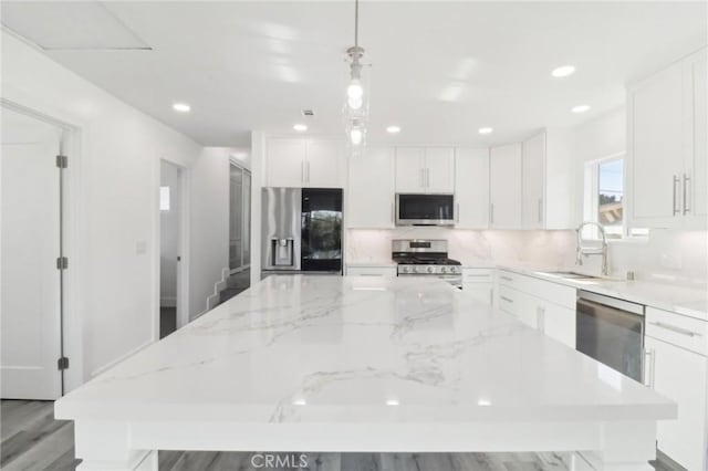 kitchen with pendant lighting, white cabinets, appliances with stainless steel finishes, a center island, and sink