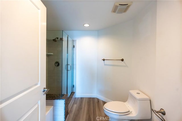 bathroom featuring toilet, a shower with door, and hardwood / wood-style flooring