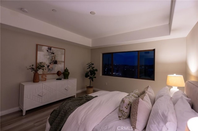 bedroom with a tray ceiling and wood-type flooring