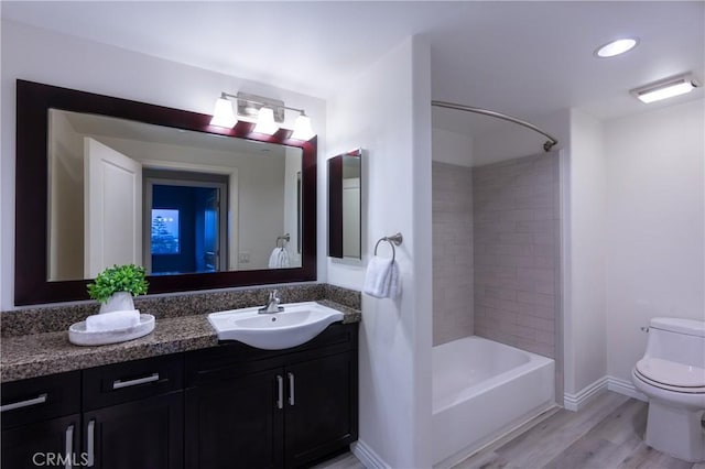 full bathroom with vanity, hardwood / wood-style flooring, toilet, and tiled shower / bath