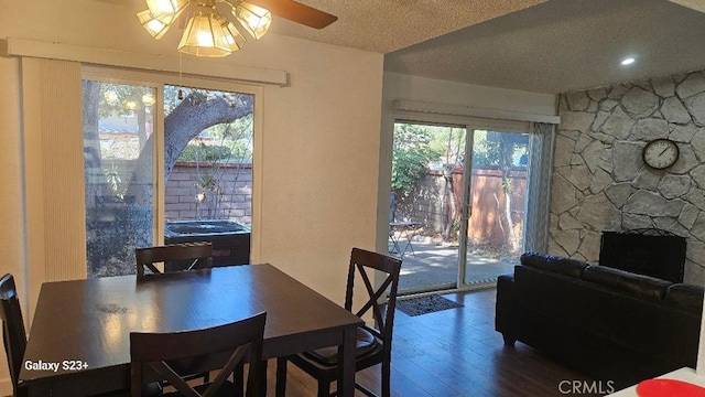 dining space featuring hardwood / wood-style floors, a fireplace, a textured ceiling, and ceiling fan