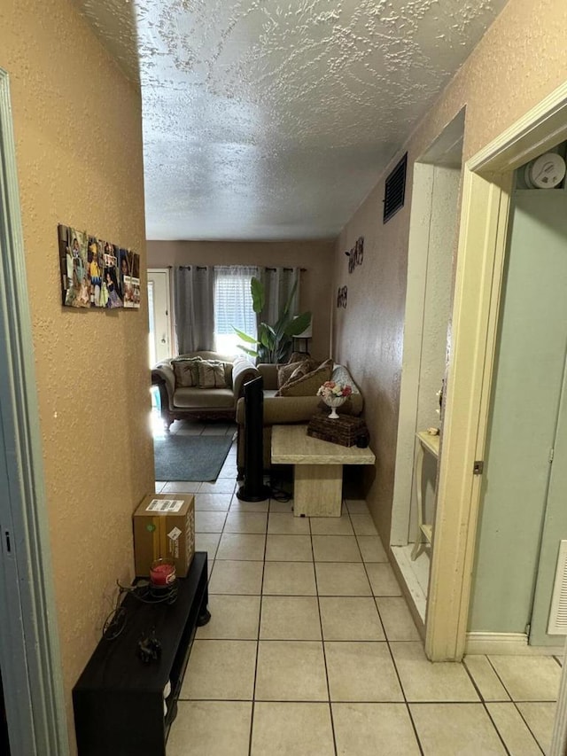 hallway with light tile patterned floors and a textured ceiling