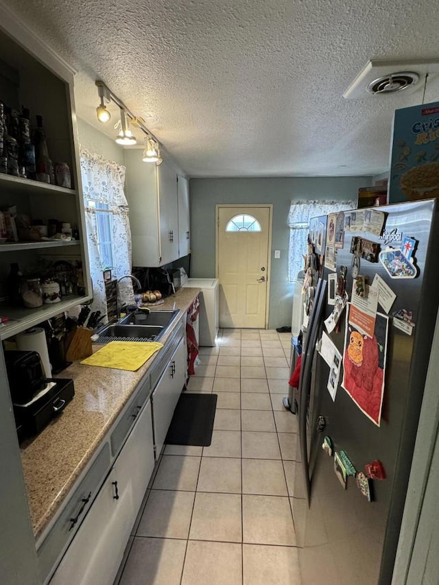 kitchen with sink, light stone counters, a textured ceiling, white cabinets, and light tile patterned flooring