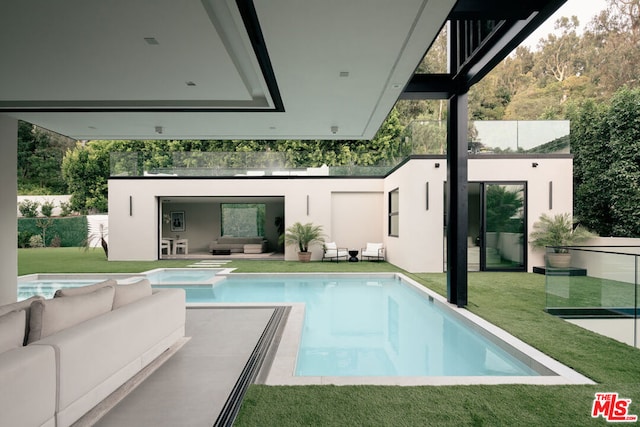 rear view of house featuring an outdoor living space, a swimming pool with hot tub, a lawn, and a patio area