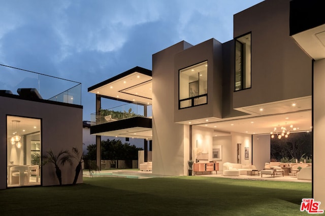 rear view of house featuring a balcony, a swimming pool, a lawn, and a patio area