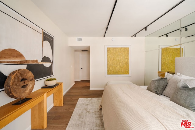 bedroom with track lighting and dark hardwood / wood-style flooring