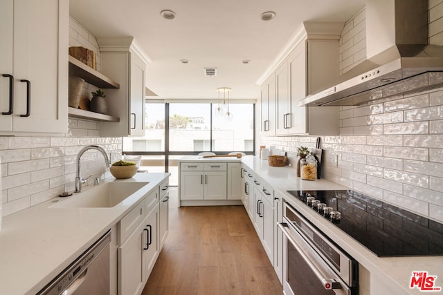 kitchen featuring wall chimney exhaust hood, light hardwood / wood-style floors, sink, appliances with stainless steel finishes, and white cabinetry