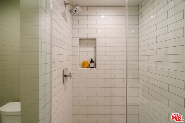 bathroom featuring a tile shower and toilet