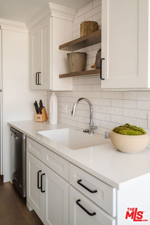 kitchen featuring white cabinets, sink, stainless steel dishwasher, dark wood-type flooring, and decorative backsplash