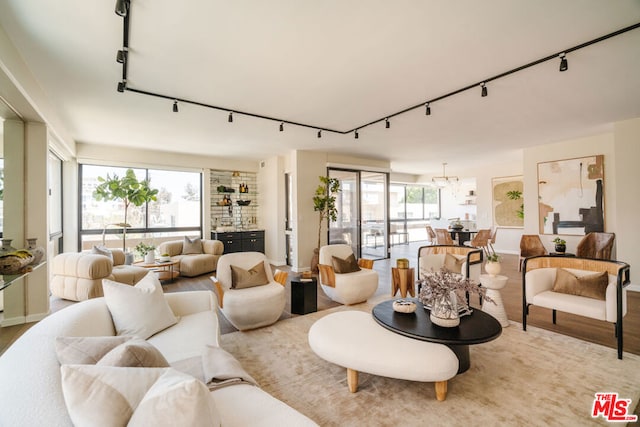 living room with a notable chandelier, light hardwood / wood-style flooring, and track lighting