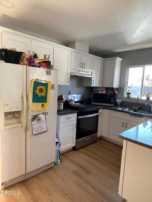 kitchen featuring light hardwood / wood-style flooring, stainless steel appliances, sink, white cabinetry, and a textured ceiling