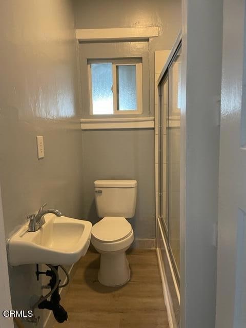 bathroom with toilet, an enclosed shower, hardwood / wood-style flooring, and sink