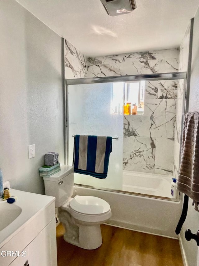 full bathroom with vanity, bath / shower combo with glass door, wood-type flooring, and toilet