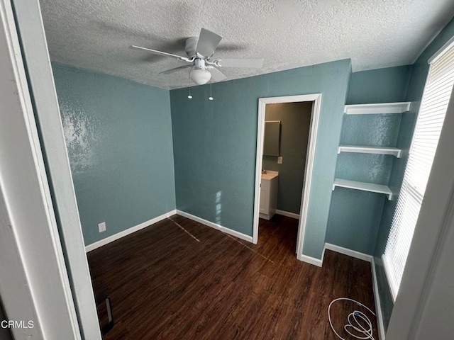 unfurnished bedroom with a textured ceiling, ceiling fan, ensuite bath, and dark hardwood / wood-style flooring