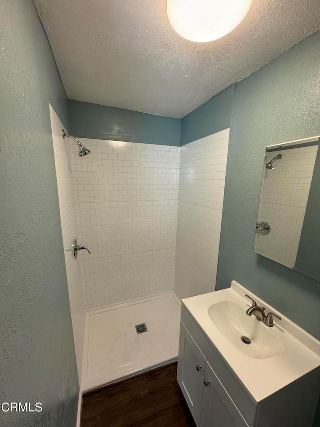 bathroom featuring vanity, a textured ceiling, tiled shower, and hardwood / wood-style floors