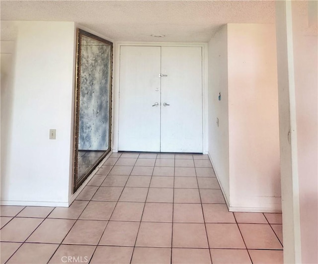 hall with light tile patterned floors and a textured ceiling