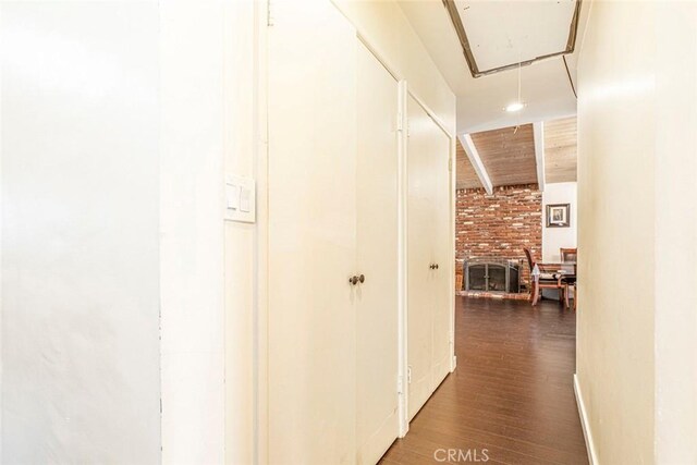 hallway with wooden ceiling, dark wood-type flooring, and brick wall