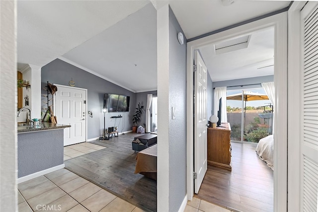 hall with sink, light hardwood / wood-style floors, ornamental molding, and lofted ceiling