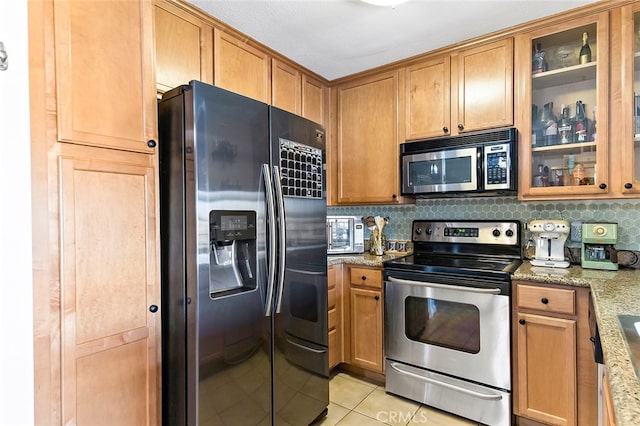 kitchen featuring light stone counters, stainless steel appliances, tasteful backsplash, and light tile patterned floors