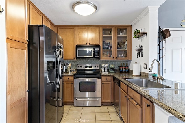 kitchen featuring light tile patterned floors, ornamental molding, dark stone countertops, sink, and stainless steel appliances