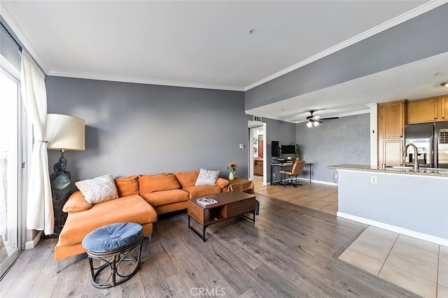 living room featuring ornamental molding, light wood-type flooring, and ceiling fan