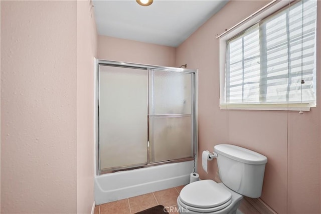 bathroom with tile patterned floors, shower / bath combination with glass door, and toilet