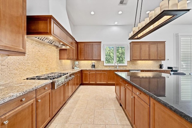 kitchen with decorative light fixtures, stone counters, backsplash, and stainless steel gas cooktop