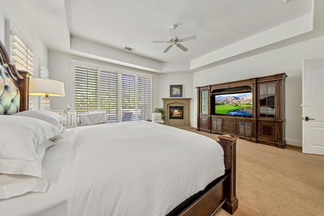 carpeted bedroom featuring a tray ceiling and ceiling fan