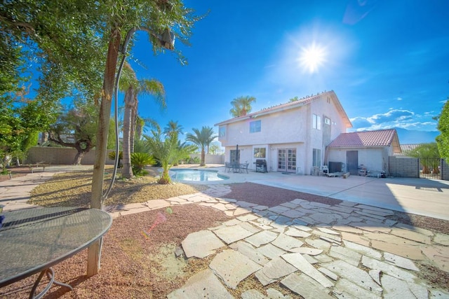 rear view of property featuring a fenced in pool and a patio area