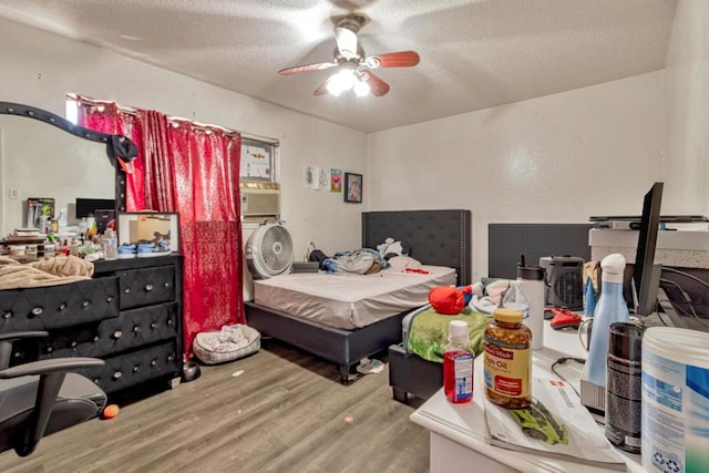 bedroom featuring ceiling fan, wood-type flooring, and a textured ceiling