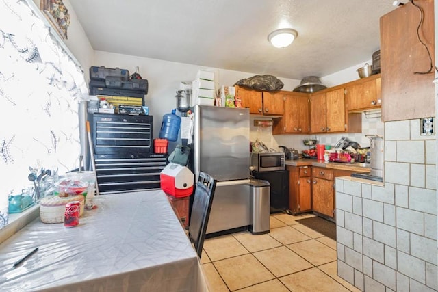 kitchen with tile countertops, light tile patterned floors, backsplash, and appliances with stainless steel finishes