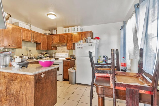 kitchen with kitchen peninsula, light tile patterned floors, a healthy amount of sunlight, and white appliances