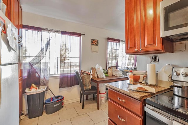 kitchen featuring light stone countertops, appliances with stainless steel finishes, and light tile patterned floors