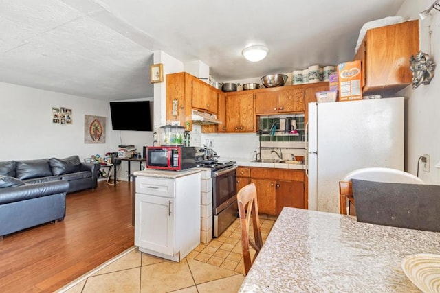 kitchen with light wood-type flooring, stainless steel range, sink, white cabinets, and white fridge