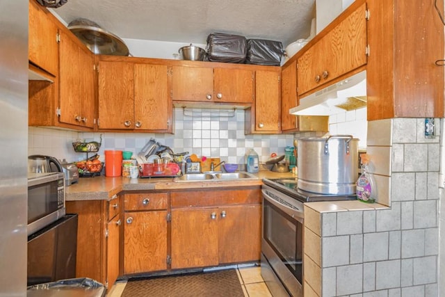 kitchen featuring decorative backsplash, light tile patterned floors, stainless steel appliances, and sink