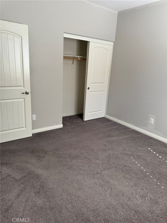 unfurnished bedroom with dark colored carpet and a closet