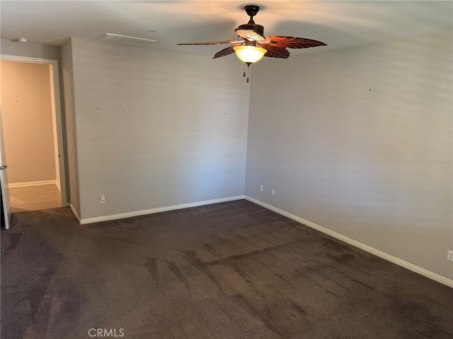 empty room with ceiling fan and dark colored carpet