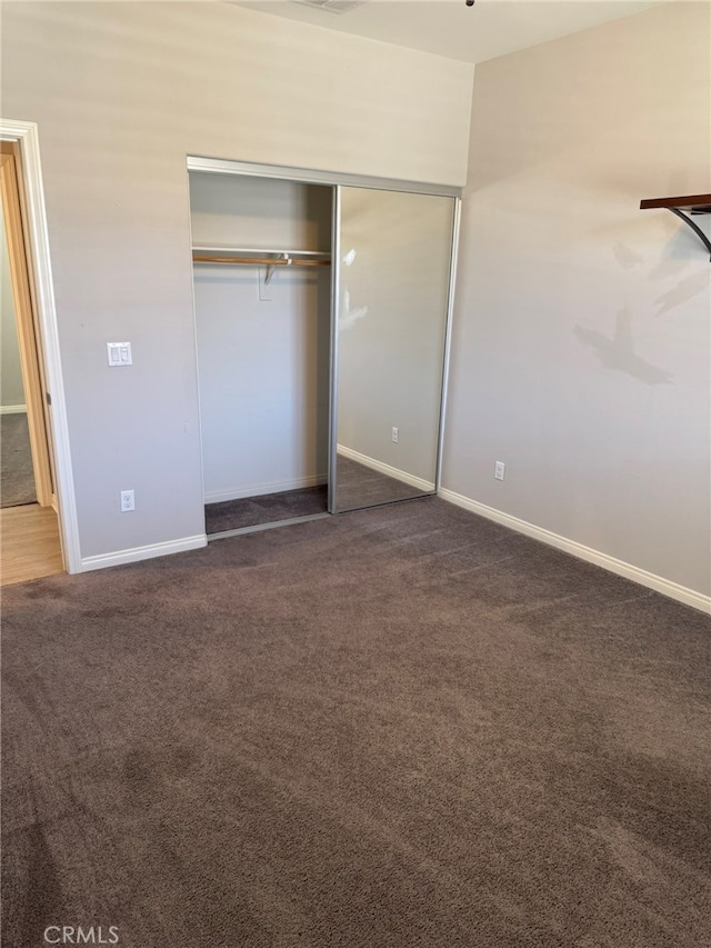 unfurnished bedroom featuring dark colored carpet and a closet