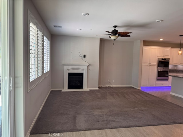 unfurnished living room with wood-type flooring and ceiling fan