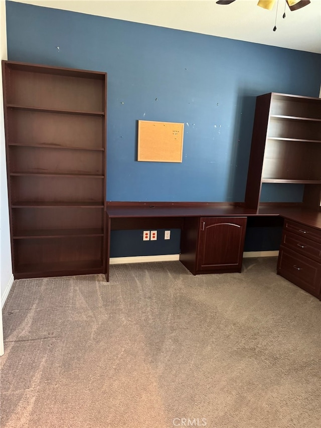 unfurnished bedroom featuring ceiling fan, light colored carpet, and built in desk