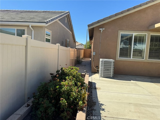 view of side of home with cooling unit and a patio