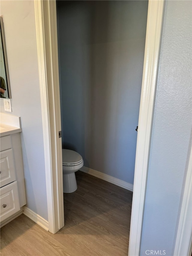 bathroom featuring wood-type flooring, vanity, and toilet