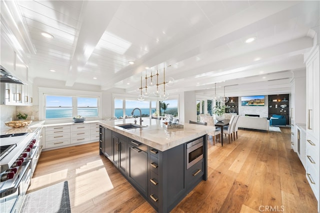 kitchen with pendant lighting, a water view, sink, beam ceiling, and white cabinetry