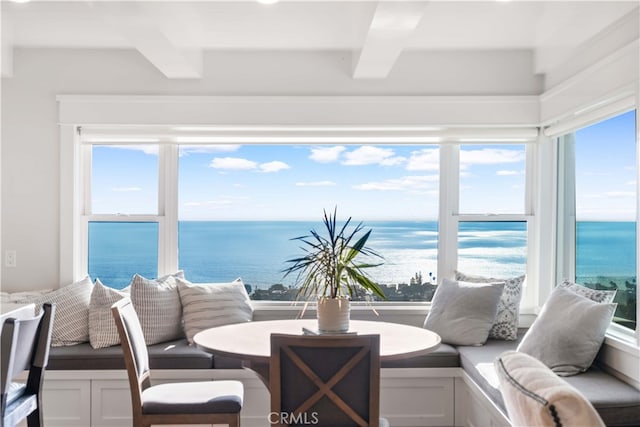 sunroom / solarium featuring beamed ceiling and a water view