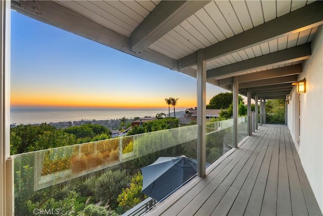 deck at dusk featuring a water view