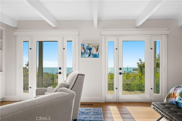 entryway with beamed ceiling, plenty of natural light, and light wood-type flooring