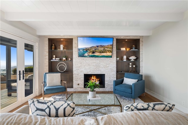 living room featuring french doors, built in features, beamed ceiling, a fireplace, and hardwood / wood-style floors